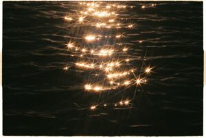 Golden sunlight sparkles on the rippling water surface, creating a magical serene atmosphere.